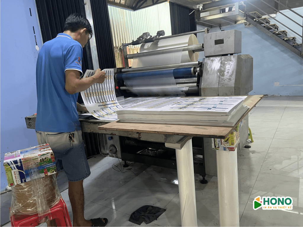 Nhân viên kỹ thuật Hono đang vận hành máy cán màng nhiệt khổ lớn để bảo vệ bề mặt tờ in sau sản xuất